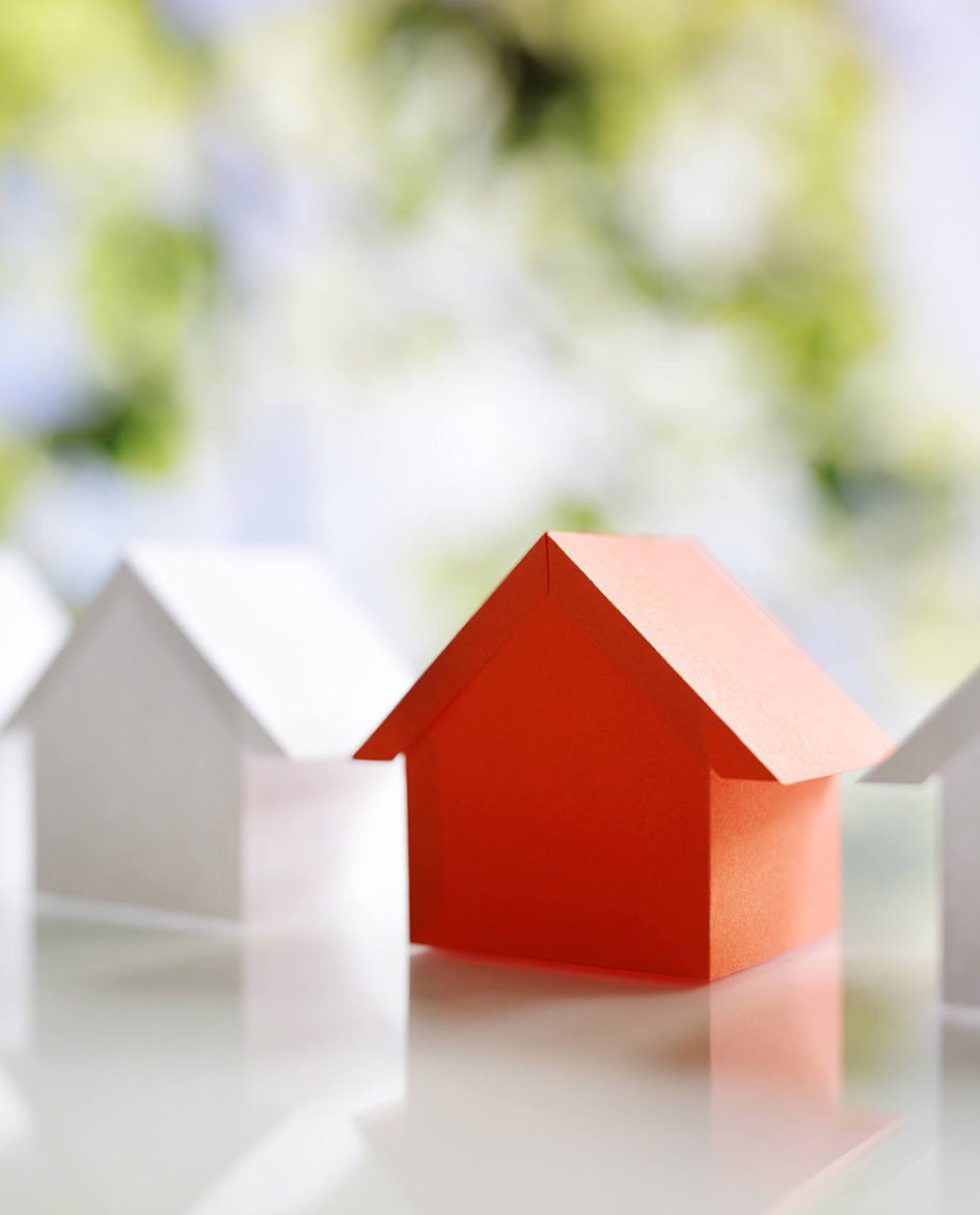 複数の白い小さな家の模型の中に赤色の家の模型が一つある画像